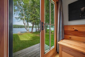 Eine Holzhütte mit einer Schiebetür zu einer Terrasse mit Blick auf einen See.