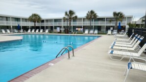 Piscina com espreguiçadeiras e palmeiras.