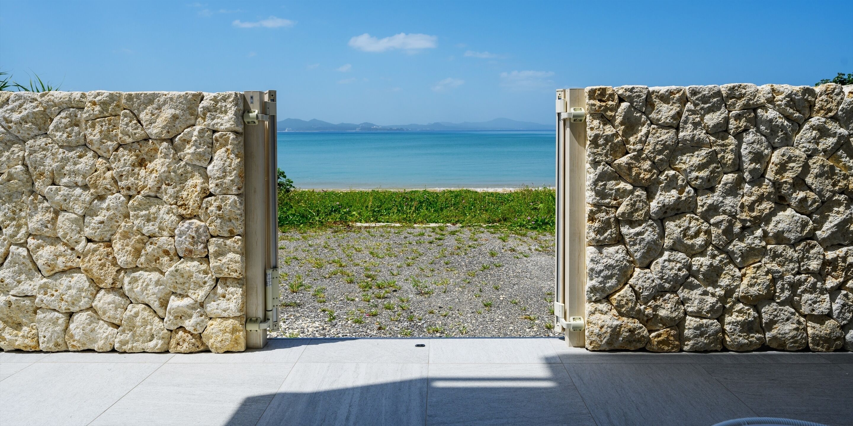 A stone wall with a view of a beach and the sea.