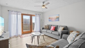 Ein Wohnzimmer mit grauem Sofa, einem weißen Couchtisch und einem Deckenventilator.