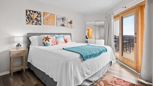 Ein Schlafzimmer mit einem Bett, einem Nachttisch, einem Fenster mit Vorhängen und einem Kunstwerk an der Wand.