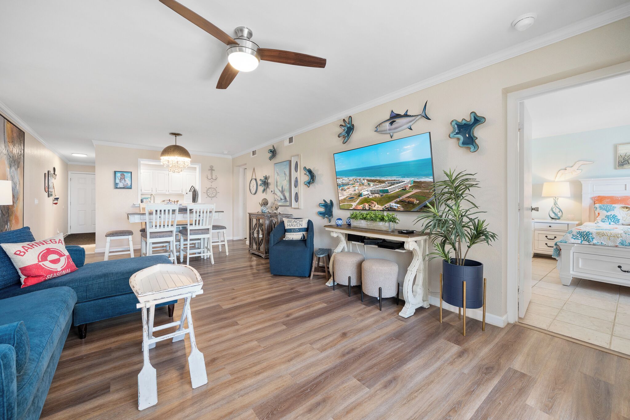 A spacious living room with a blue sofa, a dining area, and a kitchen in the background.