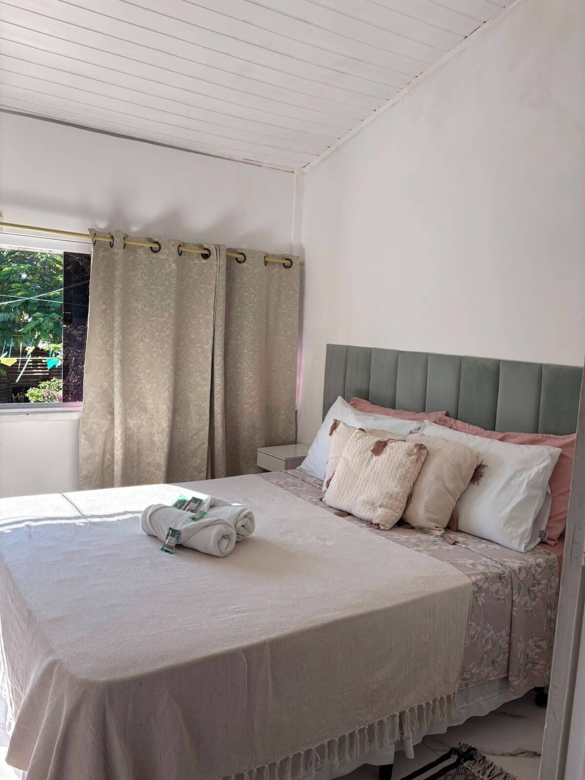 A bedroom with a bed, curtains, and a window.