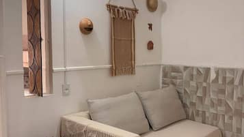 Um quarto com uma cama, uma mesinha, uma luminária na parede e um objeto decorativo na parede.