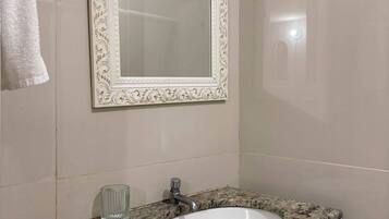 A bathroom with a marble sink, a wall-mounted mirror with an ornate frame, and a towel hanging on the wall.