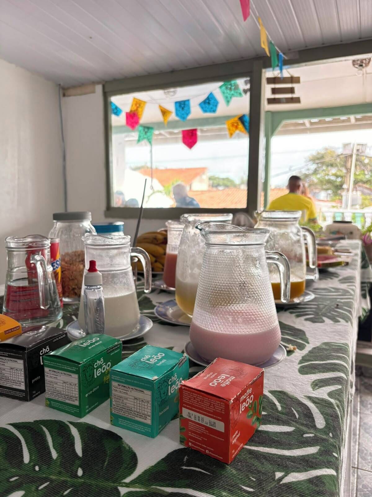 A table with various food items and drinks, including jars and boxes, in a casual dining setting.