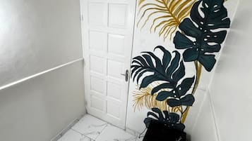 A hallway with white walls, a white door, and a tiled floor.