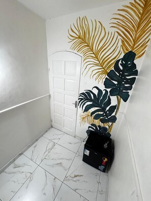 Un pasillo con paredes blancas, una puerta blanca y piso de baldosas.