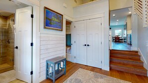 A hallway with wooden flooring, white doors, a small blue bench, and a painting on the wall. - Charming Townhouse,  Shared pool, Great Location (Port Aransas)