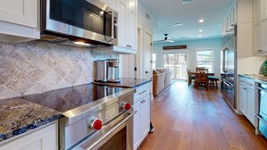 A modern kitchen with stainless steel appliances, white cabinetry, and a marble backsplash. - Charming Townhouse,  Shared pool, Great Location (Port Aransas)