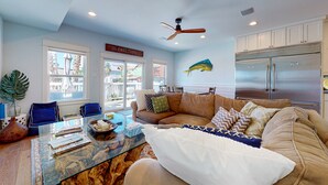 A modern living room with a glass coffee table, leather sofa, and a large fish mural. - Charming Townhouse,  Shared pool, Great Location (Port Aransas)