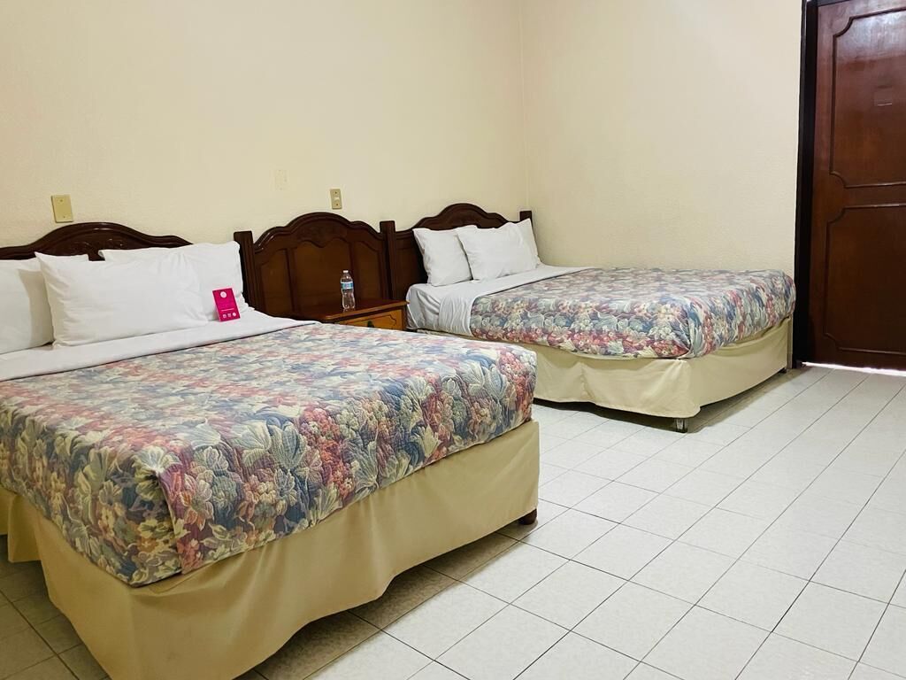 A hotel room with two beds, each with floral bedding and white pillows.