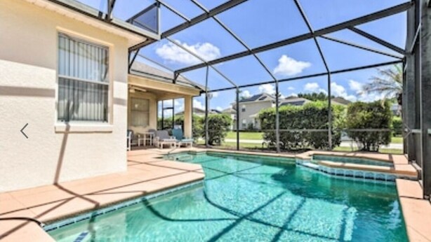 A swimming pool with a clear blue water, surrounded by a covered patio area with a view of the neighborhood.