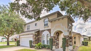 A two-story house with a stone facade, a garage, and a well-maintained lawn.