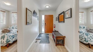 A hallway with two bedrooms, each with a bed, a bench, and framed pictures on the walls. - The Cedar - Downtown, walking distance to all the shops and restaurants! (Banff)