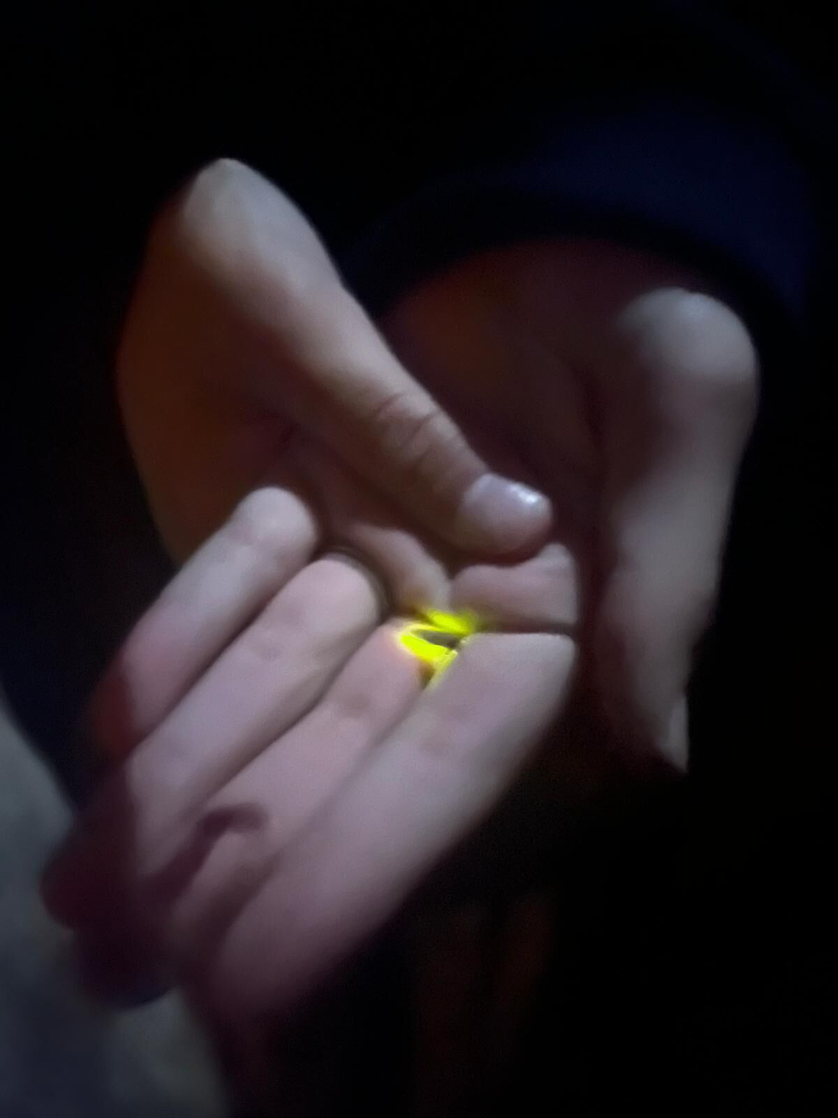 A hand holding a small, glowing object.