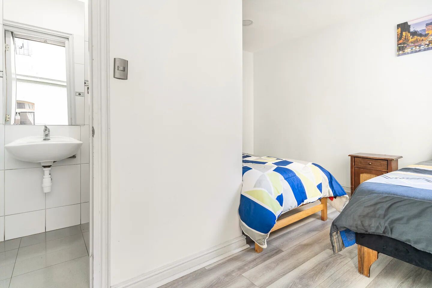 Un dormitorio con cama, mesita de noche y velador.