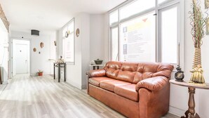 A spacious living room with a leather sofa, a small side table, and a decorative vase. - Hostal mancora (Santiago)