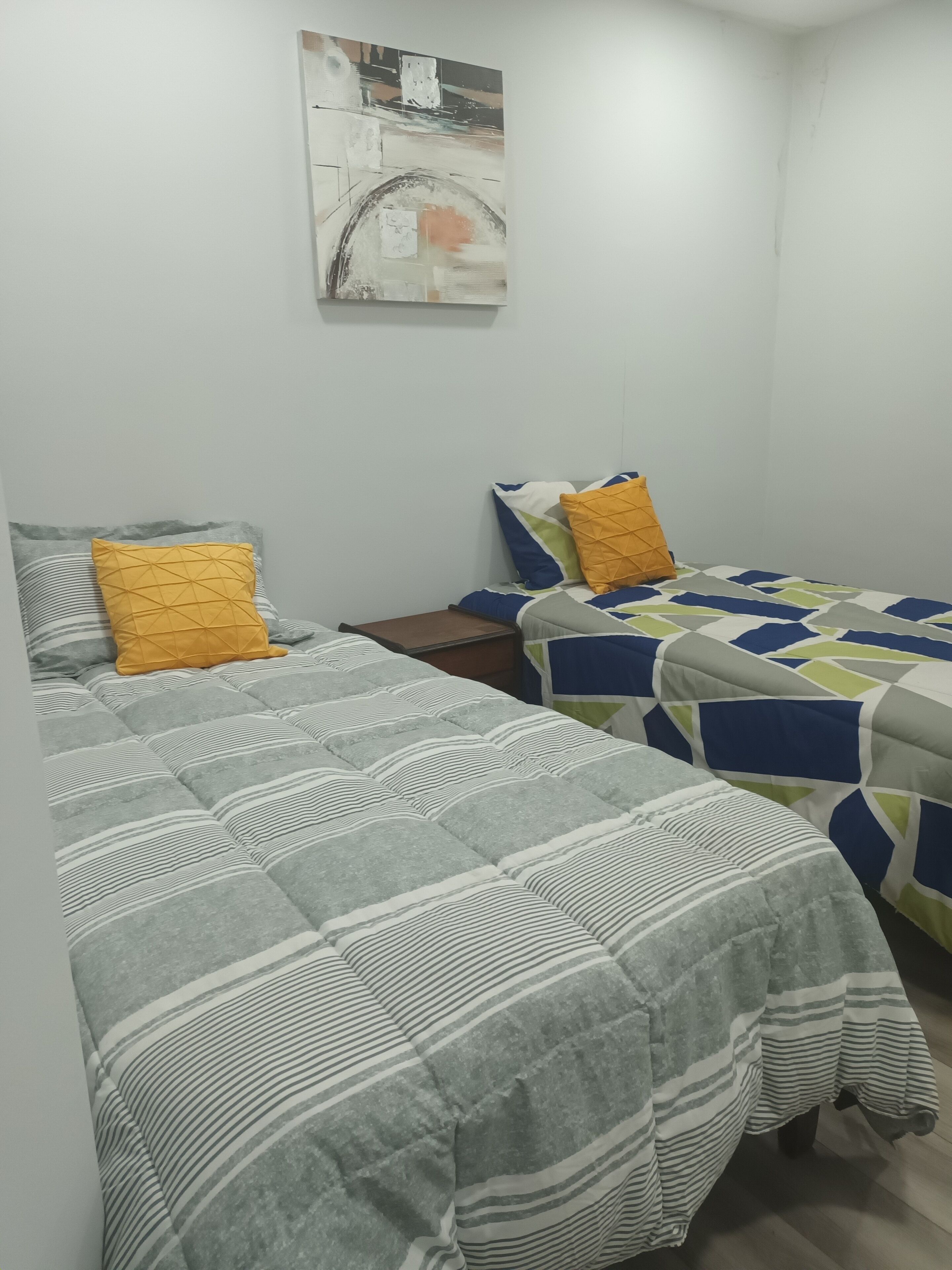 Un dormitorio con dos camas, cada una con ropa de cama a rayas y almohadas de estampado geométrico.