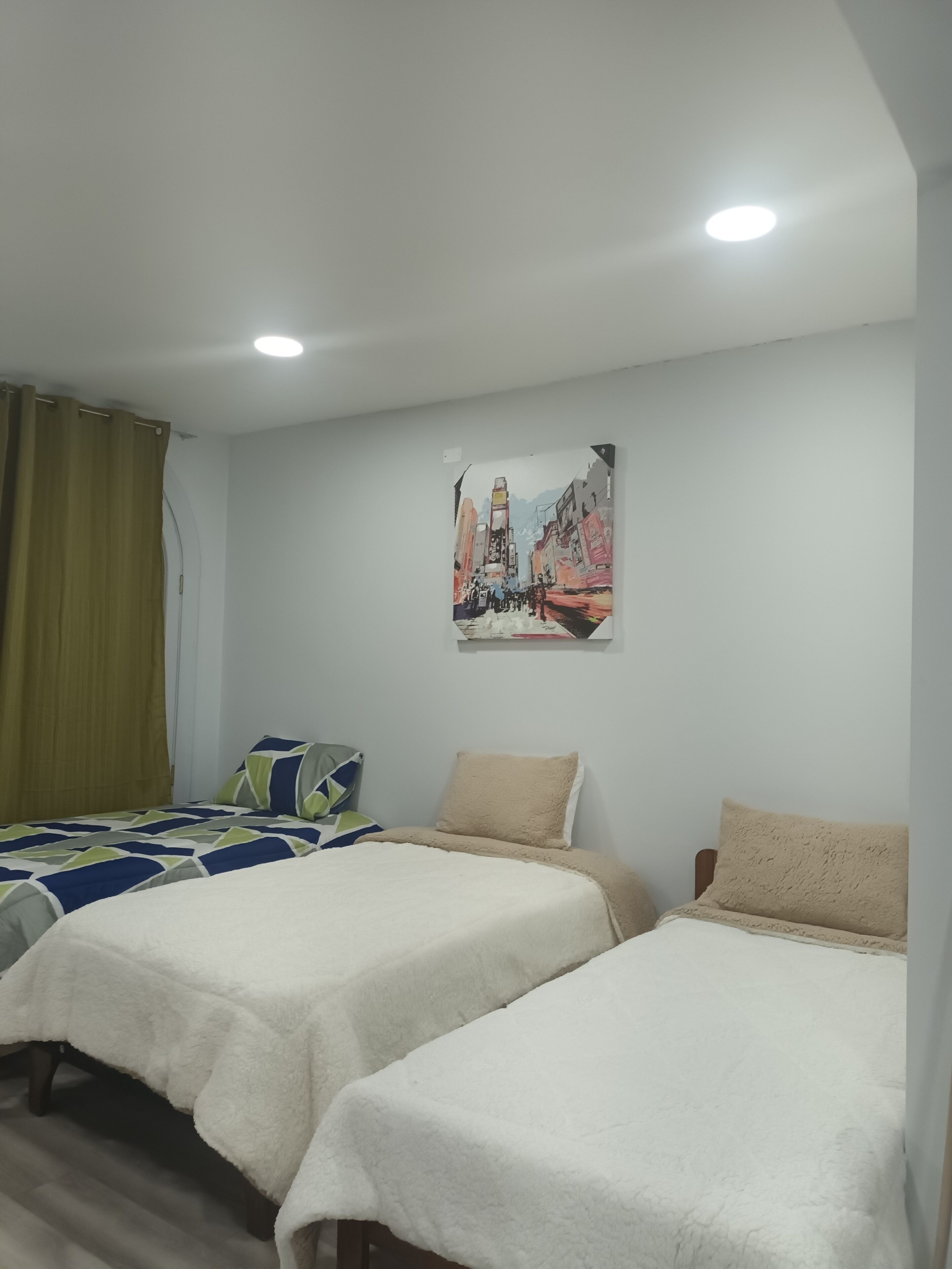 Una habitación de hotel con dos camas individuales, un cuadro en la pared y una ventana con cortinas.
