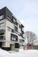Un bâtiment moderne avec une façade en béton, de nombreux balcons et une enseigne indiquant « HINZAN BALI ».