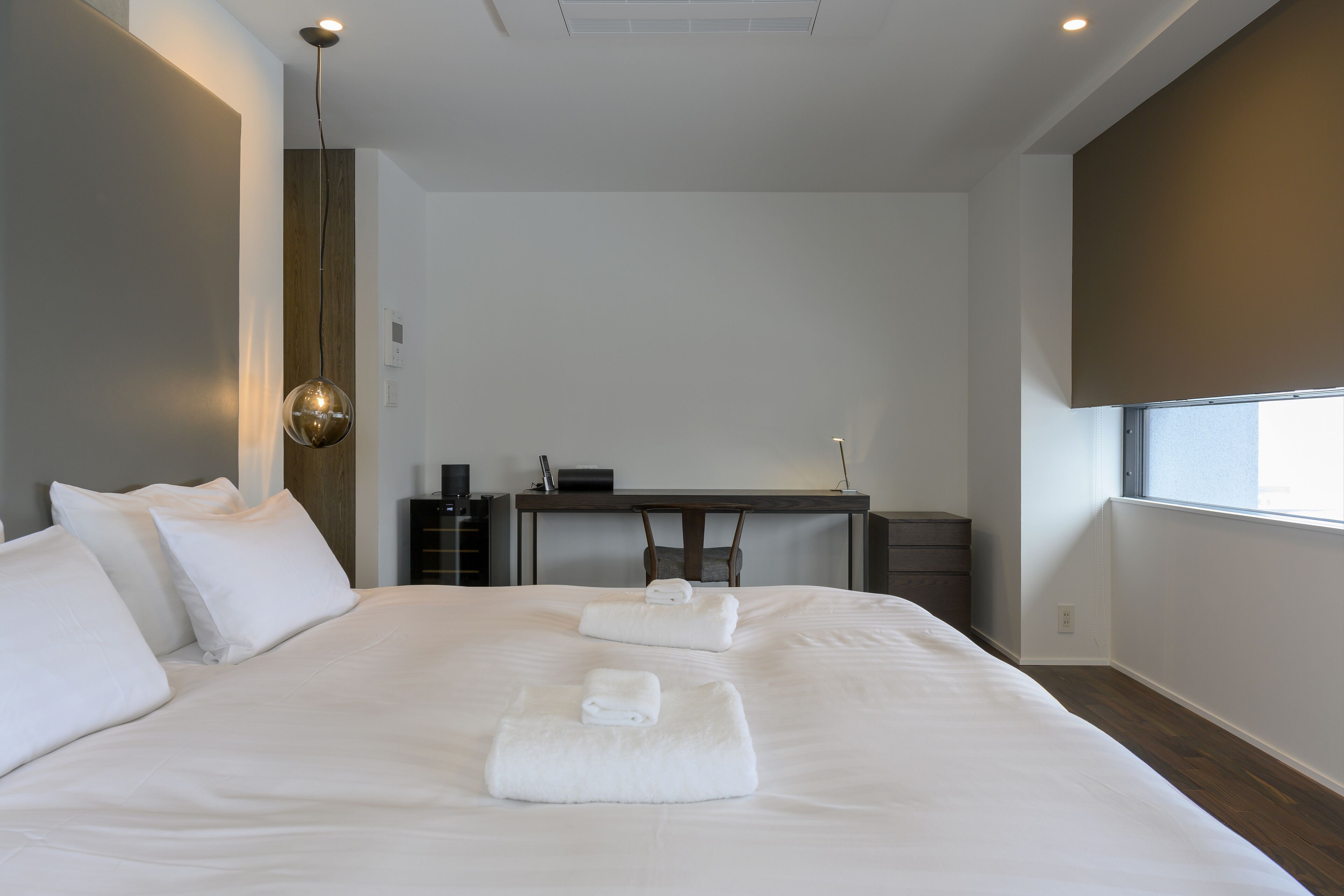 A modern hotel room with a large bed, a desk, and a window.