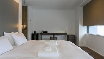 A modern hotel room with a large bed, a desk, and a window.