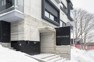 Un bâtiment moderne doté d’une façade en béton et d’une entrée en bois.