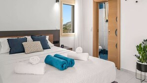 Ein modernes Schlafzimmer mit einem großen Bett, einem Nachttisch, einem Fenster mit Blick und einer Tür zum Badezimmer.