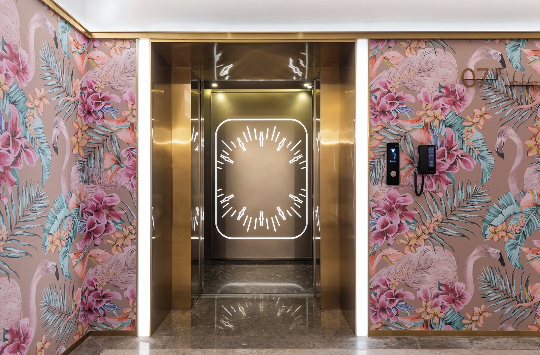 An elevator with a digital clock displaying the time, surrounded by floral wallpaper.