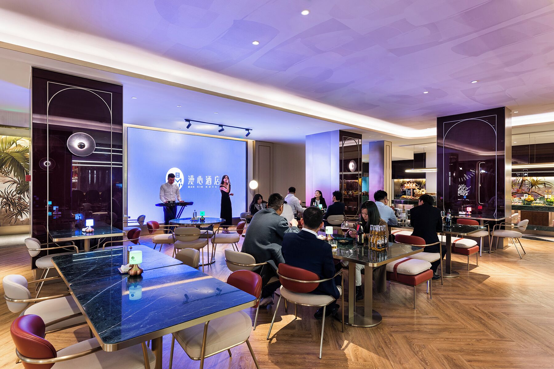 A hotel conference room with a stage, seating, and a bar area.