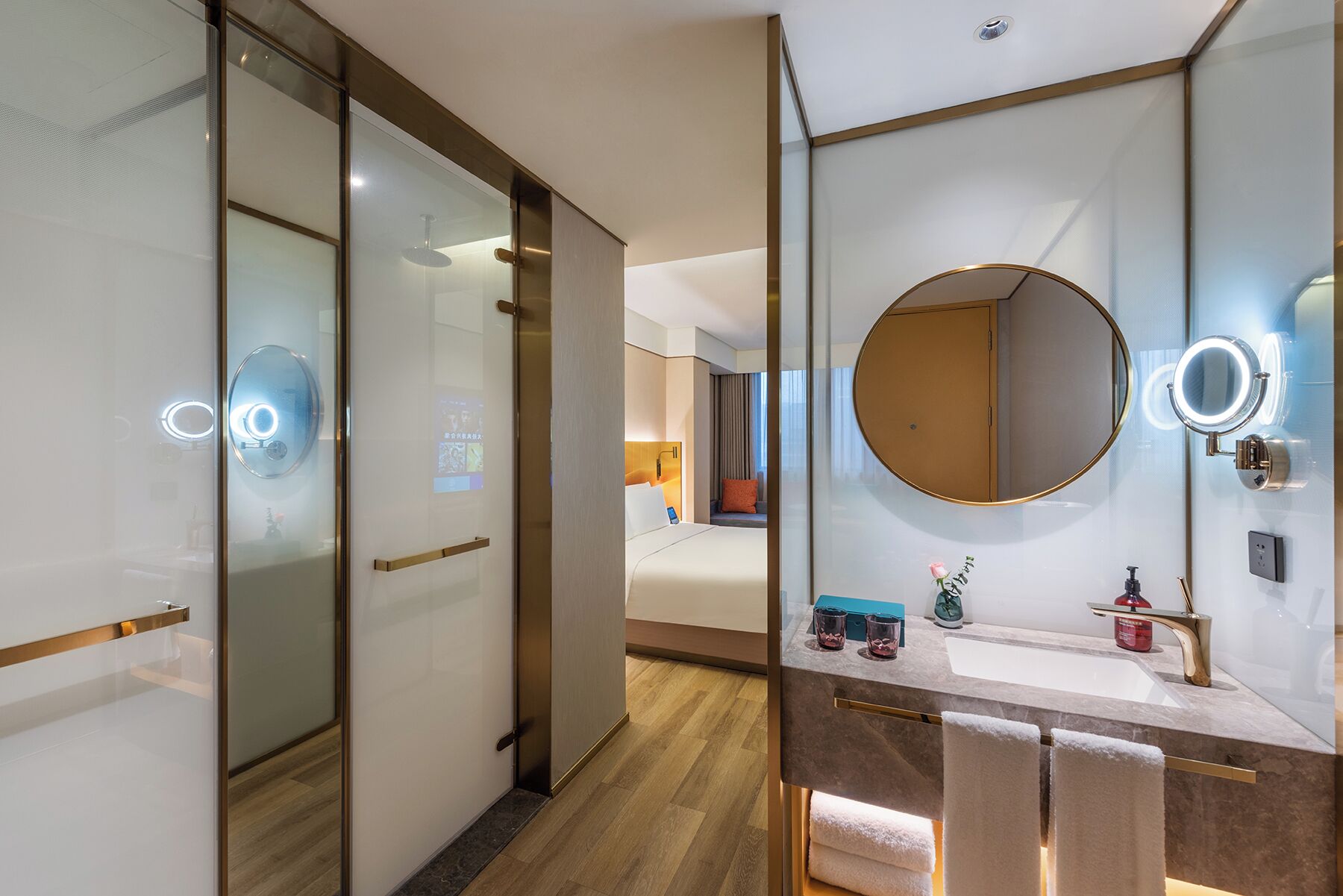 A hotel room with a large mirror, a vanity with a sink, and a bed with a headboard.