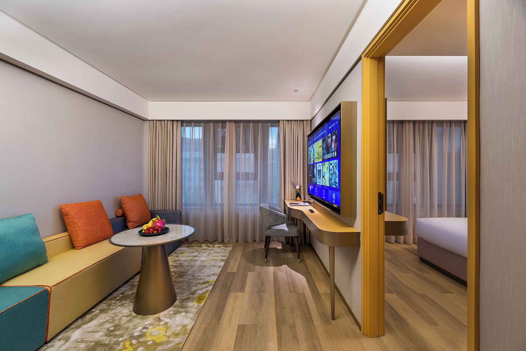 Habitación de hotel con sofá, una mesita redonda, televisión y cama.
