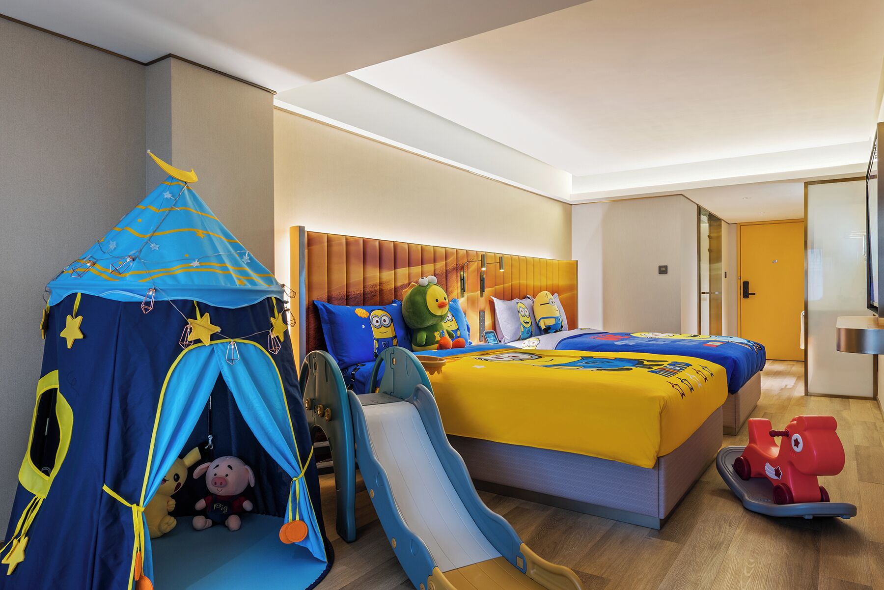 Une chambre d’hôtel avec un lit, une tente et une voiture jouet.