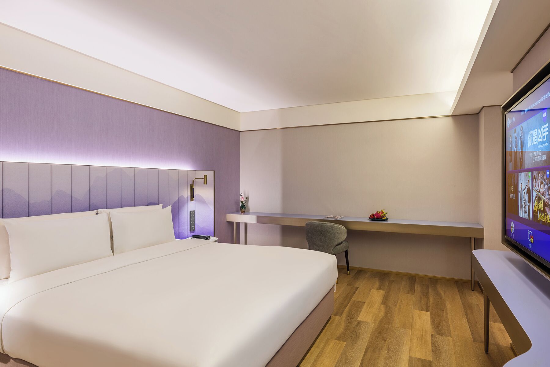 A modern hotel room with a large bed, a desk, and a television.