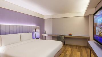 Una habitación de hotel moderna con una cama grande, un escritorio y un televisor.