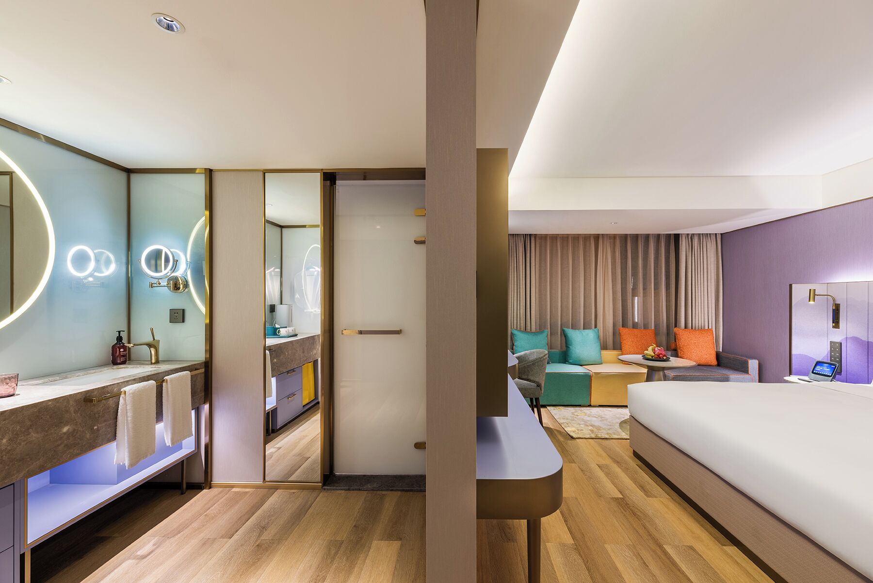 Et moderne hotelværelse med badeværelse, sofa, seng og skrivebord.