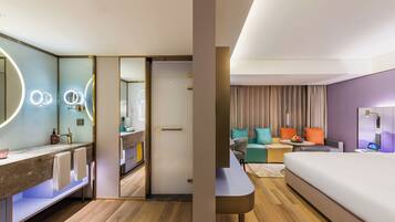Una habitación de hotel moderna con baño, sofá, cama y escritorio.