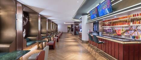A modern bar area with seating and a digital menu display.