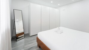 Ein modernes Schlafzimmer mit Bett, Kleiderschrank und Spiegel.
