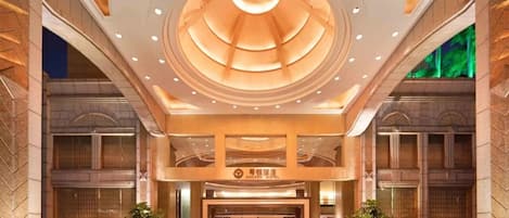 A hotel entrance with a modern design, featuring a large circular skylight and a prominent entrance with a sign.