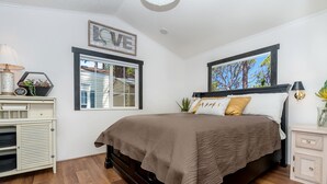 Ein Schlafzimmer mit Bett, Nachttisch, Kommode, Fenster und Wanddekoration.