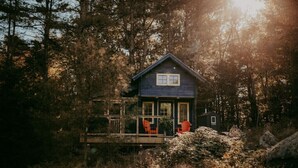 A cabin with a porch, surrounded by trees and rocks. - Glamphouse Muskoka
 (Gravenhurst)