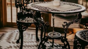 A round table with a white candle on it, a patterned rug, and a black wrought iron chair. - Glamphouse Muskoka
 (Gravenhurst)