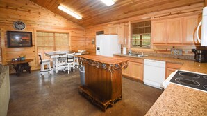L’intérieur d’une cabane en bois comprend un espace cuisine avec un îlot central, un réfrigérateur blanc et des armoires en bois.