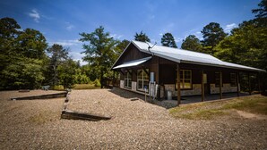 Une cabane rustique avec un toit en métal, de grandes fenêtres et une allée gravillonnée.