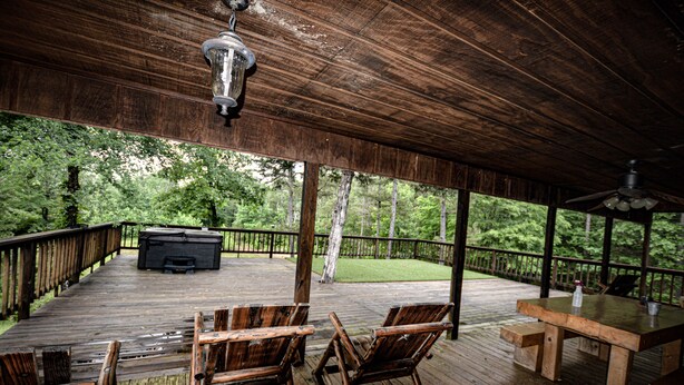 Une terrasse en bois avec une table et des chaises, un barbecue et une vue sur la forêt.