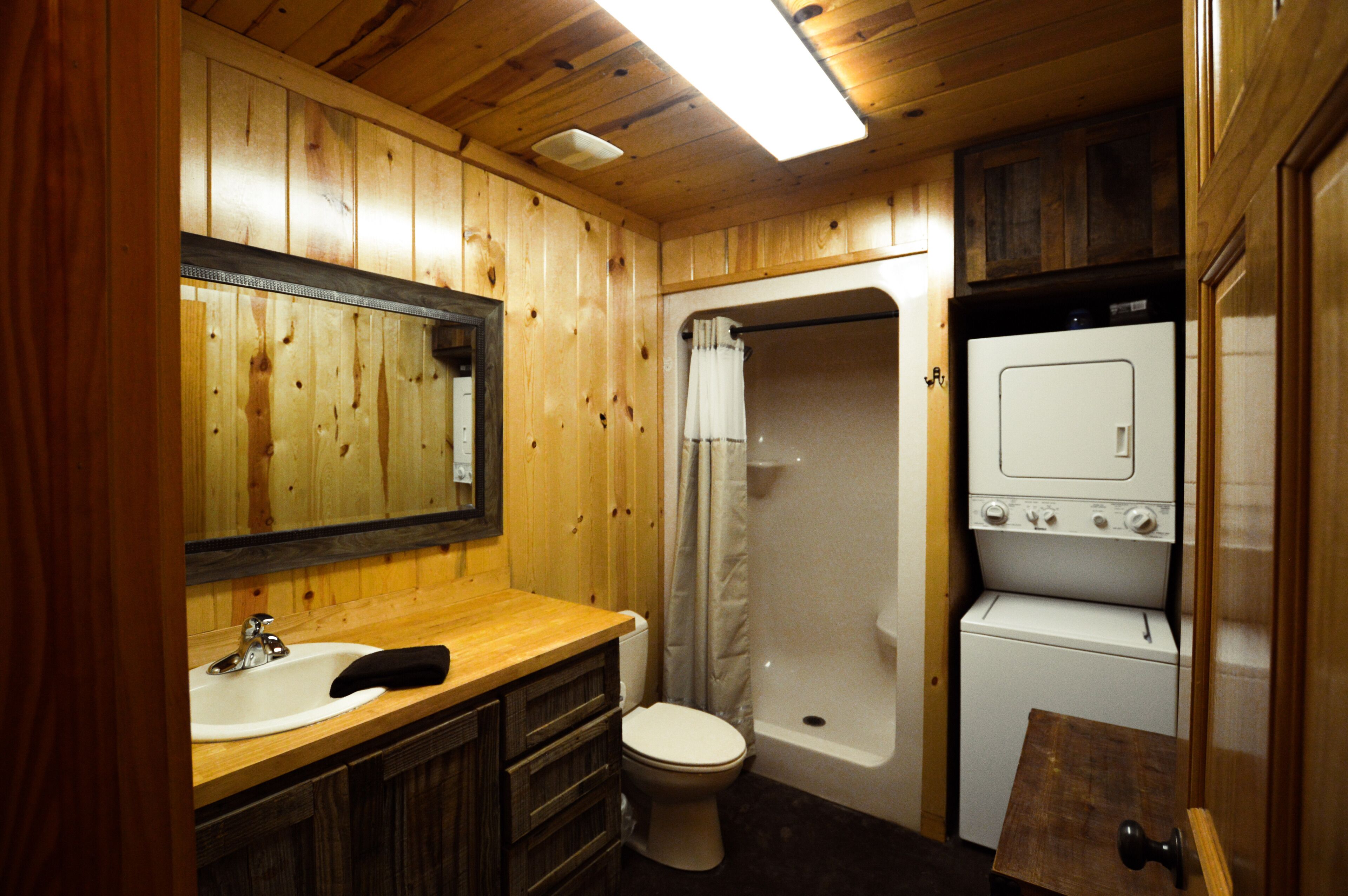 Une salle de bain en bois équipée d’un lavabo, de toilettes, d’une douche et d’un lave-linge.