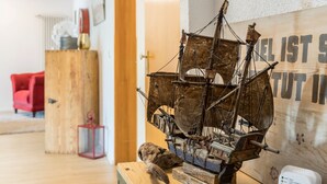 A model ship on display, a wooden cabinet, a red chair, and a wall with text.