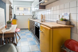 Cocina compacta con un refrigerador amarillo, un lavamanos y una ventana con vistas.